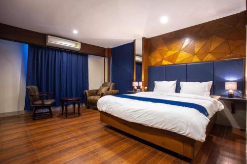 a hotel room with a large bed and a chair at Vince Sakon in Sakon Nakhon