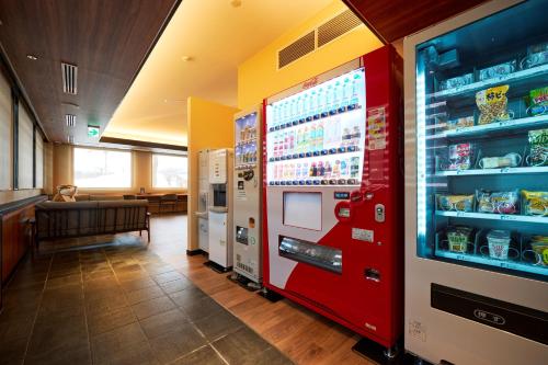 a red vending machine in a restaurant with a table at Hotel B4T Kakunodate in Senboku
