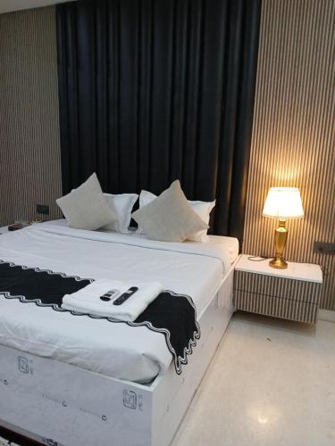 a bedroom with a large white bed with a lamp at Bell Rooms Hotel in Noida