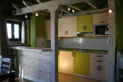 a kitchen with green and white cabinets in a room at Apartamentos Rincón del Puerto in San Vicente de la Barquera