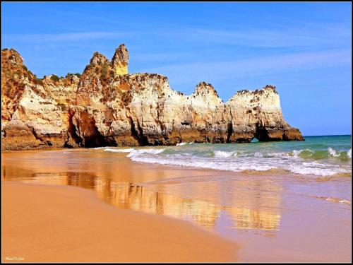 una playa con rocas en el agua y el océano en Clube Praia Mar by amcf, en Portimão