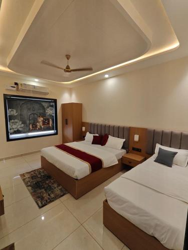 a bedroom with two beds and a tv on the wall at Hotel Brijraj Dham in Govardhan
