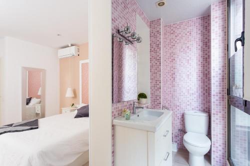 uma casa de banho branca com uma parede de azulejos cor-de-rosa em Casa Cosi Letamendi em Barcelona
