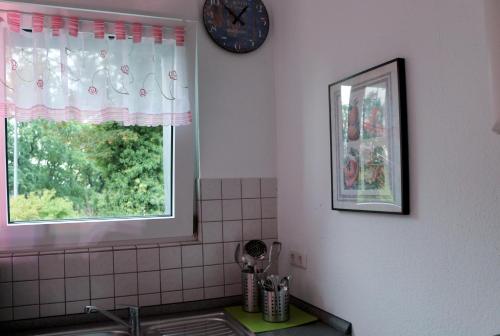 a kitchen with a sink and a clock and a window at Gästewohnung Mönchengladbach in Mönchengladbach