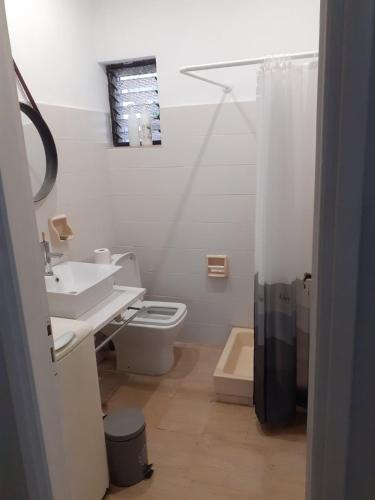 a white bathroom with a sink and a toilet at Dream house steps from sea in Pídima Kyrás