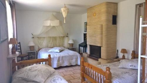une chambre avec deux lits et une cheminée dans l'établissement La Figalie, à Saint Jean du Pin