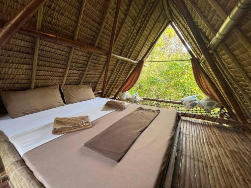 a bed in a thatched room with a window at Ecocio Explorations in Coron