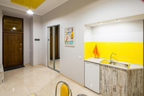 a kitchen with a sink and a yellow accent wall at Apartment on Pekarska street зі світлом! in Lviv