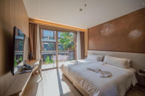 a bedroom with a bed and a desk and a window at Riverton Hotel in Samut Songkhram