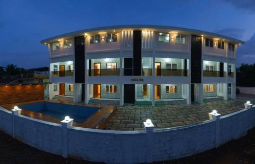 a large building with a pool in front of it at Gayathri Nest in Udupi