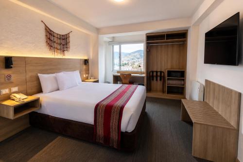 a hotel room with a large bed and a desk at Ecoterra Essentials San Blas in Cusco