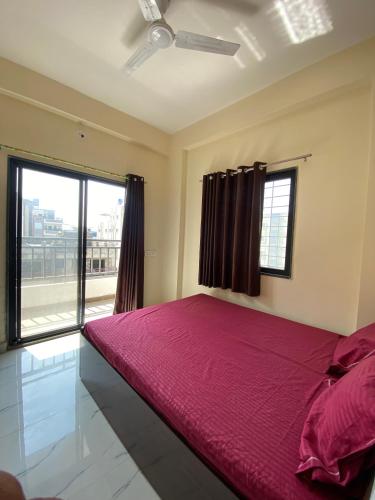 a bedroom with a large red bed with a window at Joy Suites and Hostel in Pune