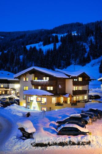a building with cars parked in the snow at night at Frühstückspension Anja in Kleinarl