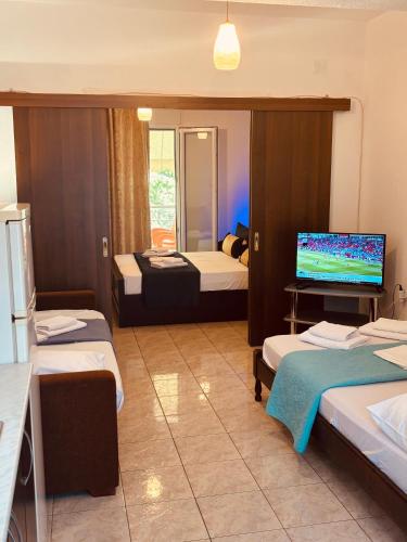 a hotel room with three beds and a television at Studio Nikol koutsoupia in Kokkino Nero