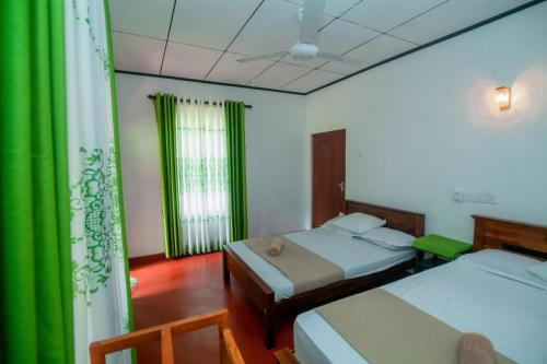 a bedroom with two beds and a green curtain at Zenvora Rainforest Villa in Deniyaya