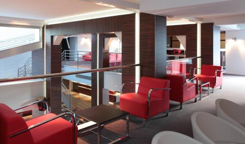 a waiting room with red chairs and tables at Hôtel Le Méditerranée in Lourdes