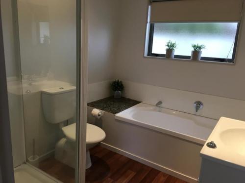 a bathroom with a toilet and a tub and a sink at Relaxing Beach Side House in Porirua