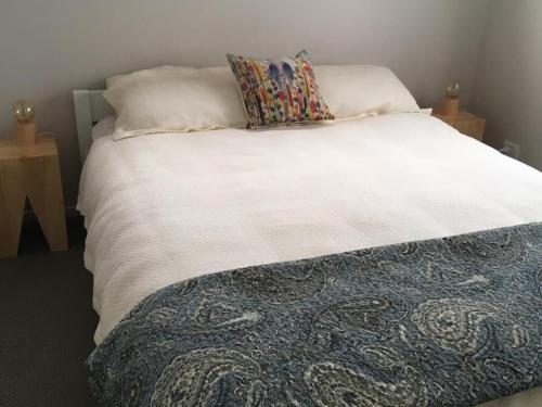 a bed with a white blanket and pillows on it at Relaxing Beach Side House in Porirua
