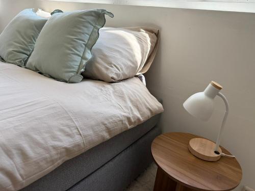 a bed with four pillows and a table with a lamp at LITTLENEIGHBOUR in Pingjum