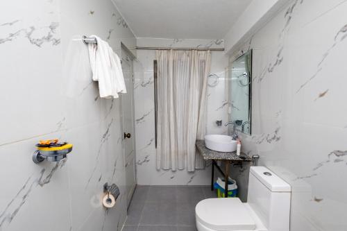 a white bathroom with a toilet and a sink at Hotel Outfitter Nepal in Kathmandu