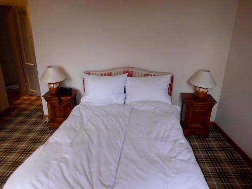 a bed with white sheets and two night stands with lamps at Hotel Freihof in Wiesloch