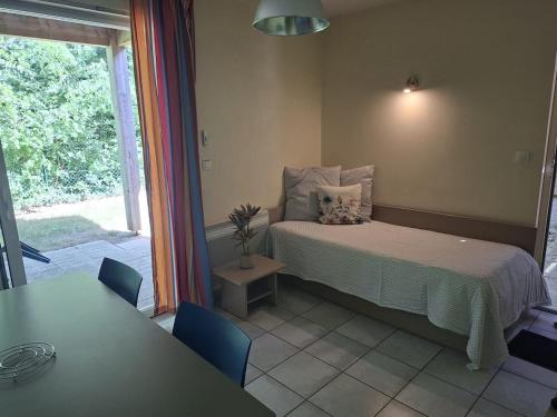 a bedroom with a bed and a table and a window at Cottage Mansart piscine tout équipé in Chaveignes