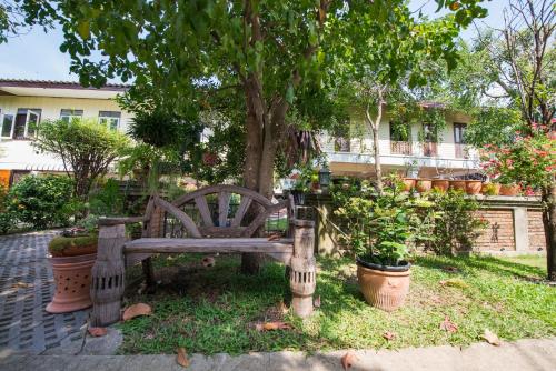 a wooden bench sitting under a tree in a yard at Phuttal Residence in Phra Nakhon Si Ayutthaya