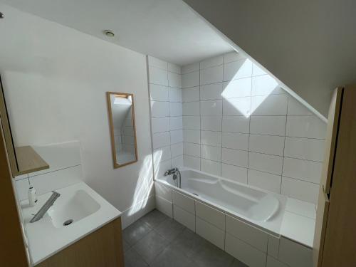 a white bathroom with a tub and a sink at Maisons avec terrasse et parking in Colmar