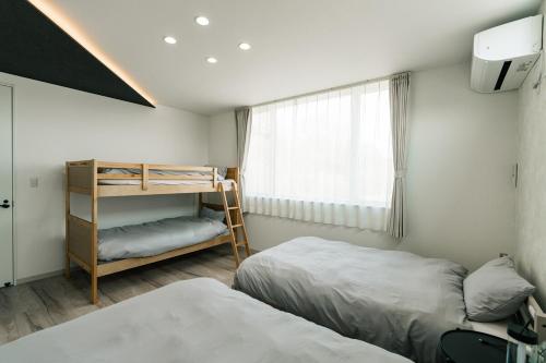 a bedroom with two beds and a bunk bed at AOI Villa Biei in Biei