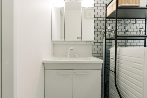 a white bathroom with a sink and a mirror at AOI Villa Biei in Biei