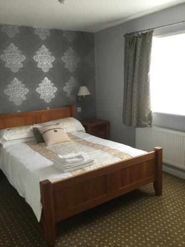 a bedroom with a bed with white sheets and a window at The Haymaker Inn in Chard