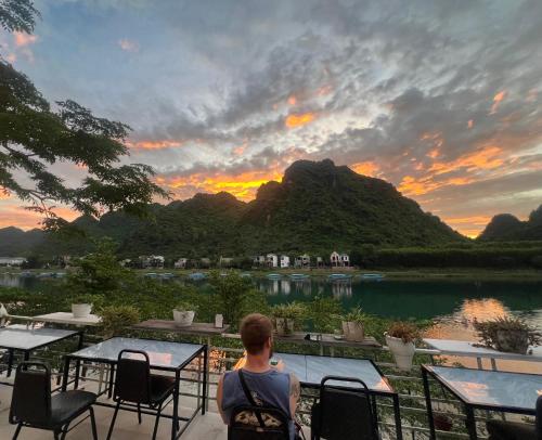 a man sitting at a table watching the sunset at Phong Nha Coco House - Riverstay & Mountain View in Phong Nha