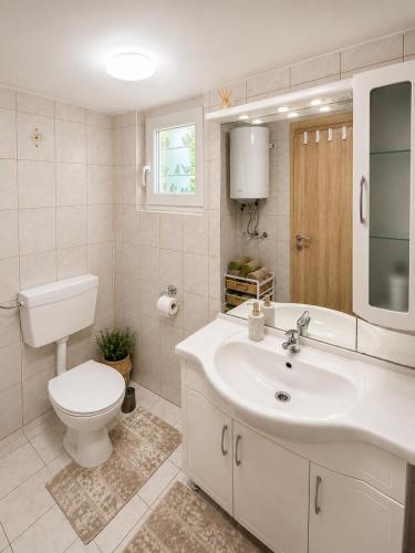 a white bathroom with a toilet and a sink at Bungalow Perun in Blejska Dobrava