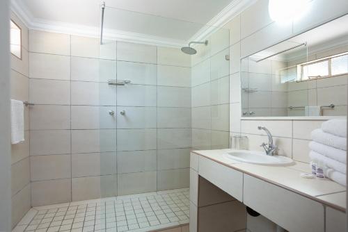 a white bathroom with a shower and a sink at Merino Inn Hotel in Colesberg