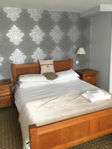 a bedroom with a bed and two night stands and a wall at The Haymaker Inn in Chard