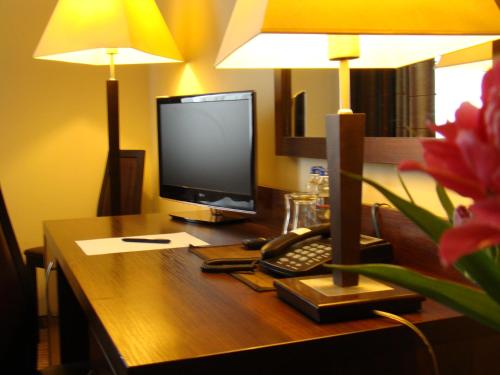 a desk with a computer monitor and a keyboard and a lamp at Hotel Azalia & Spa in Niepołomice