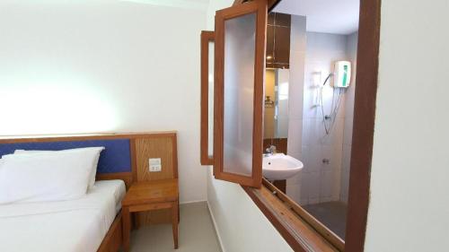 a bathroom with a bed and a sink and a mirror at J2 Hotel in Mae Sot
