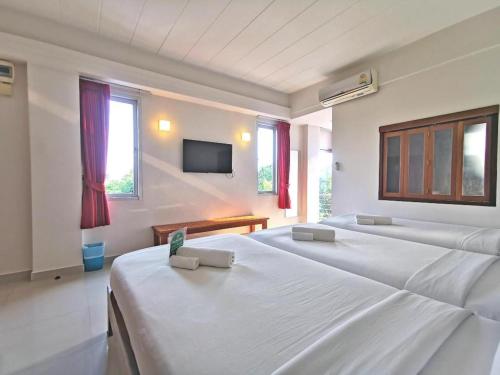 a bedroom with two beds and a tv on the wall at J2 Hotel in Mae Sot