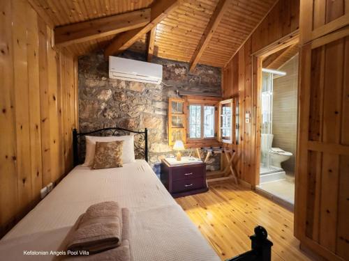 a bedroom with a bed and a stone wall at Kefalonian Luxury Villas in Kástron