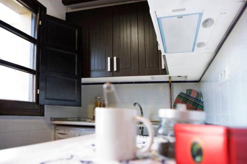 a kitchen with black cabinets and a sink and a counter at Apartamentos Santillana del Mar in Santillana del Mar