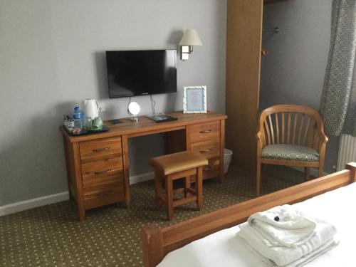 a hotel room with a desk with a television and a chair at The Haymaker Inn in Chard