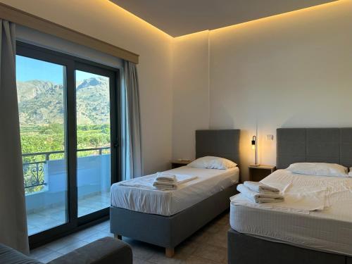 a hotel room with two beds and a large window at Blue Sky in Frangokastello