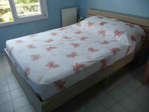 uma cama com um cobertor branco com flores vermelhas em Chambre chez l'habitant Nice Baie des Anges em Nice
