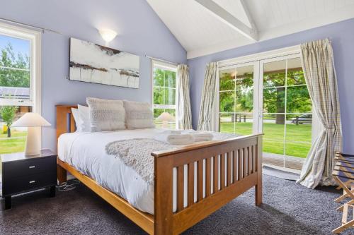 a bedroom with a large bed and windows at Arrow Junction Cottage in Arrowtown