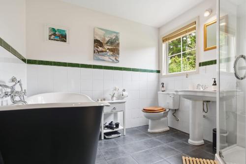 a bathroom with a tub and a toilet and a sink at Arrow Junction Cottage in Arrowtown