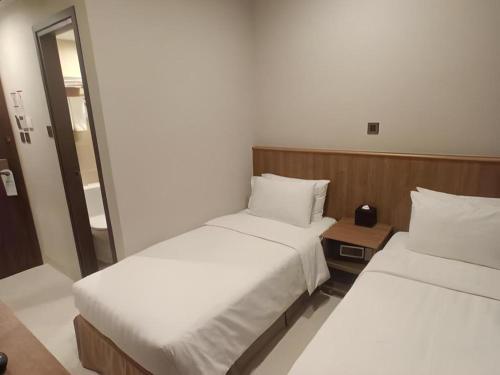 two beds in a hotel room with a mirror at WE Hotel Kowloon in Hong Kong