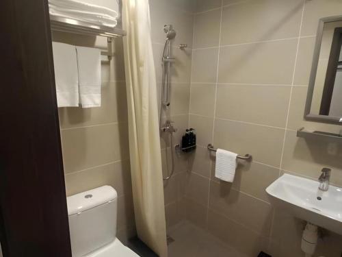a bathroom with a shower and a toilet and a sink at WE Hotel Kowloon in Hong Kong