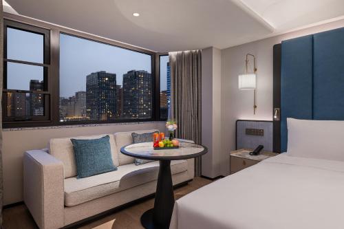 a hotel room with a bed and a couch and a window at Manxin Hotel Beijing Guomao Jianguomen in Beijing