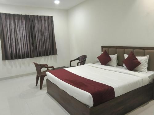 a bedroom with a bed with two chairs and a window at Shubham Resort in Bhilwara