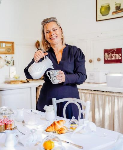 a woman standing in a kitchen holding a tea pot at Au Clair de Vianne Ce sont les petits détails qui font la différence in Vianne